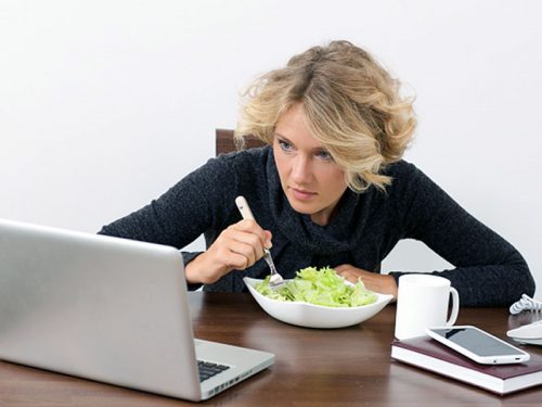 パソコンを見ながら食事をする女性